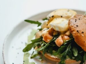 Delicious gourmet salmon burger topped with arugula and hollandaise sauce on a rustic plate.